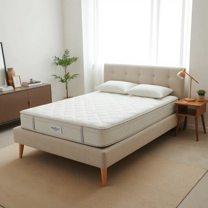 Neatly made bed with a simple modern mattress in a bright, minimal bedroom