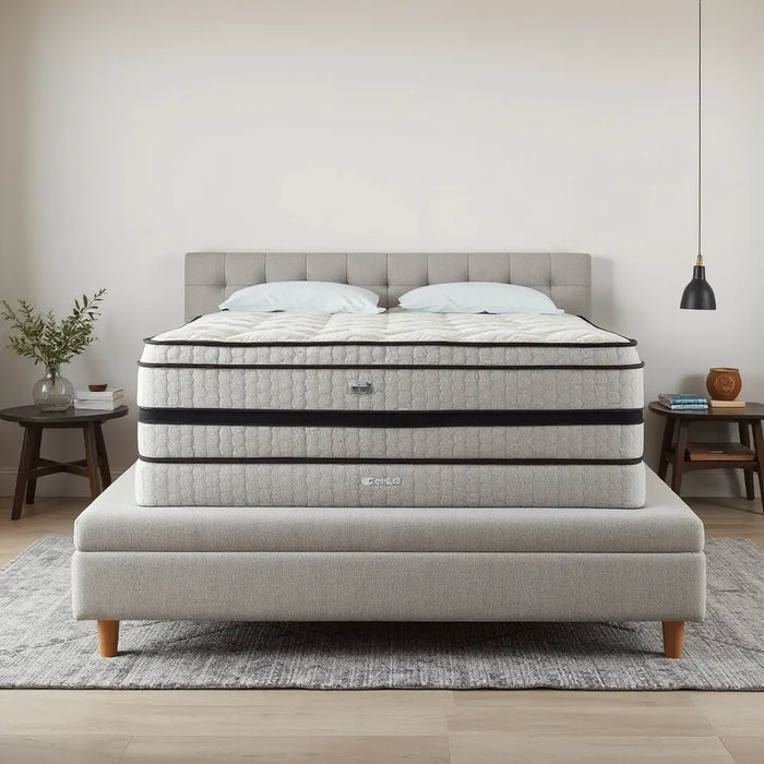 A modern bed featuring a clearly thick, extra tall mattress with layered comfort and neutral bedding