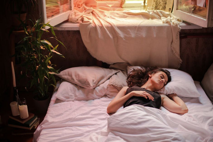 A woman sleeps peacefully in a sunlit bedroom, capturing the essence of a tranquil morning.