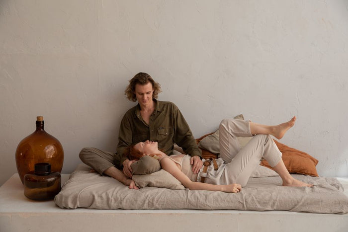 Positive couple in casual clothes chilling on soft mattress in light room with minimalistic interior in daytime