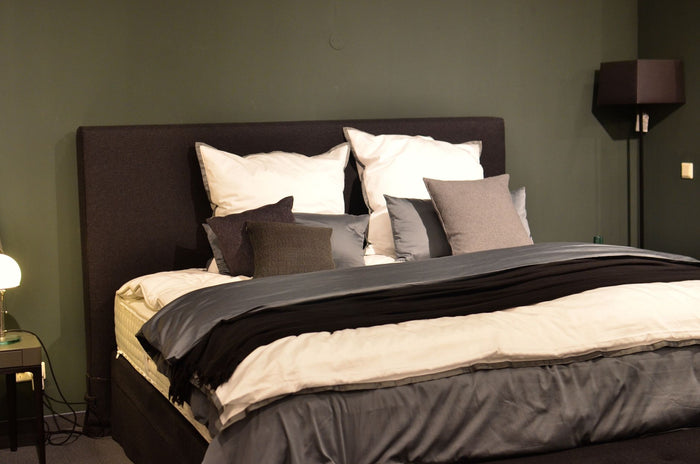 Creative design of bed with collection of cushions and cover between lamps in house