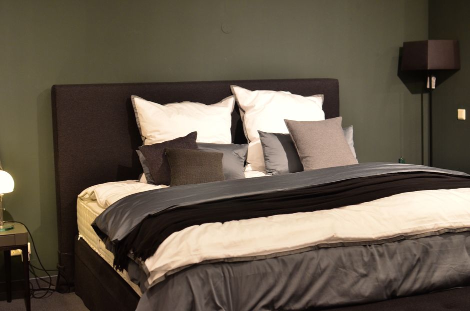 Creative design of bed with collection of cushions and cover between lamps in house