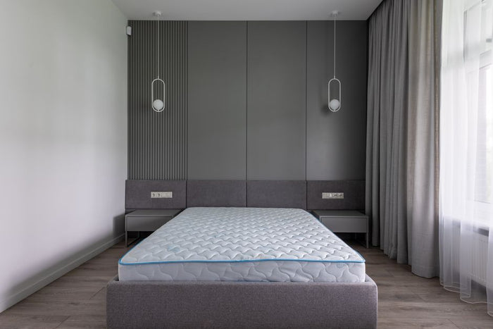 Comfortable bed with convenient modern mattress in contemporary interior of spacious gray bedroom