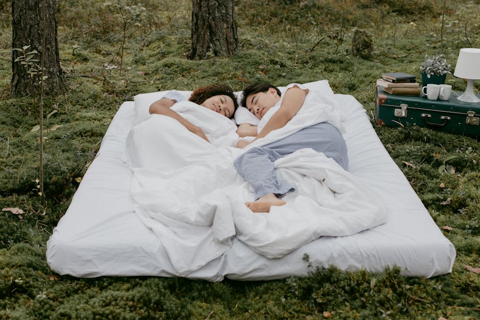 A couple relaxes in the forest, lying on a comfortable mattress surrounded by nature's tranquility.