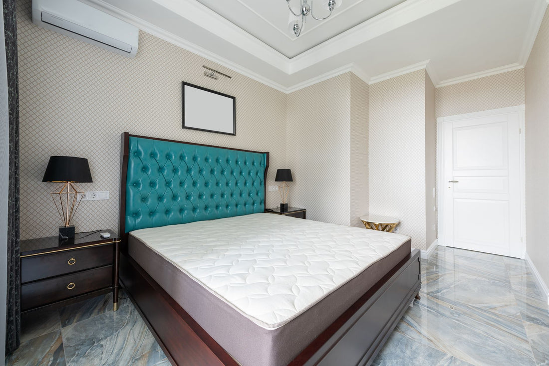 Bed with mattress and upholstery between lamps on bedside tables on tiled floor in light house