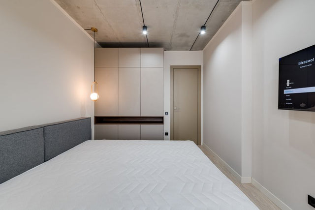 A sleek and modern minimalist bedroom featuring a bed, furniture, and ambient lighting.