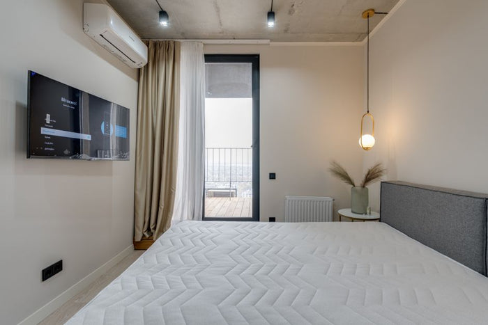 Minimalistic bedroom featuring a balcony, flat screen TV, and elegant lighting.