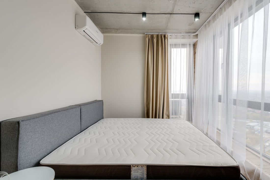 Spacious modern bedroom with a clean mattress and large windows for natural light.