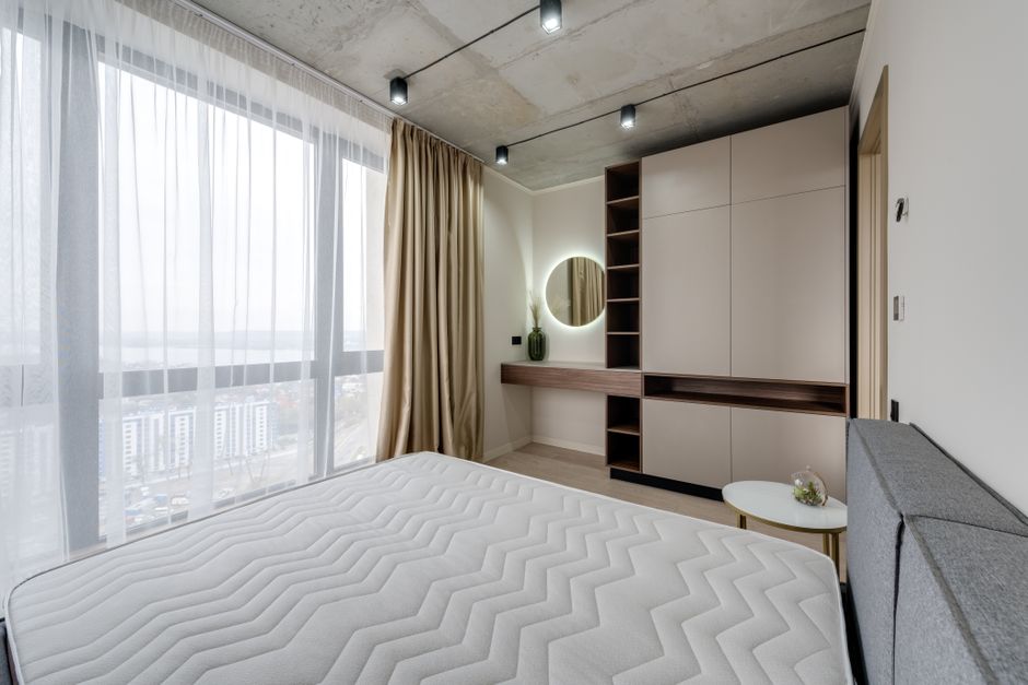 Bright minimalist bedroom with a large window and modern furniture design.