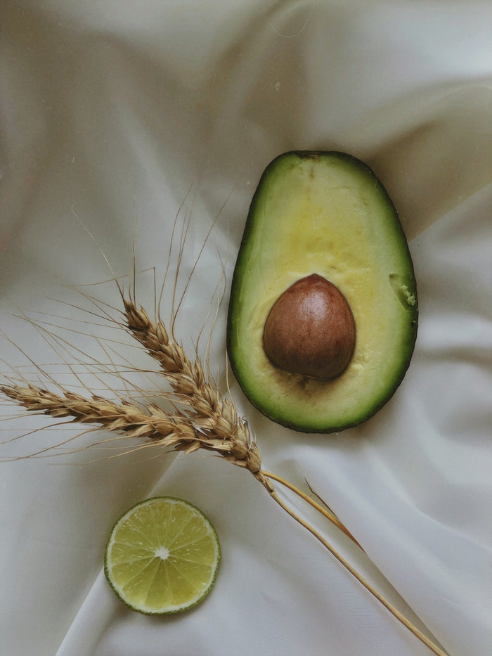an avocado and a slice of lime on a white cloth