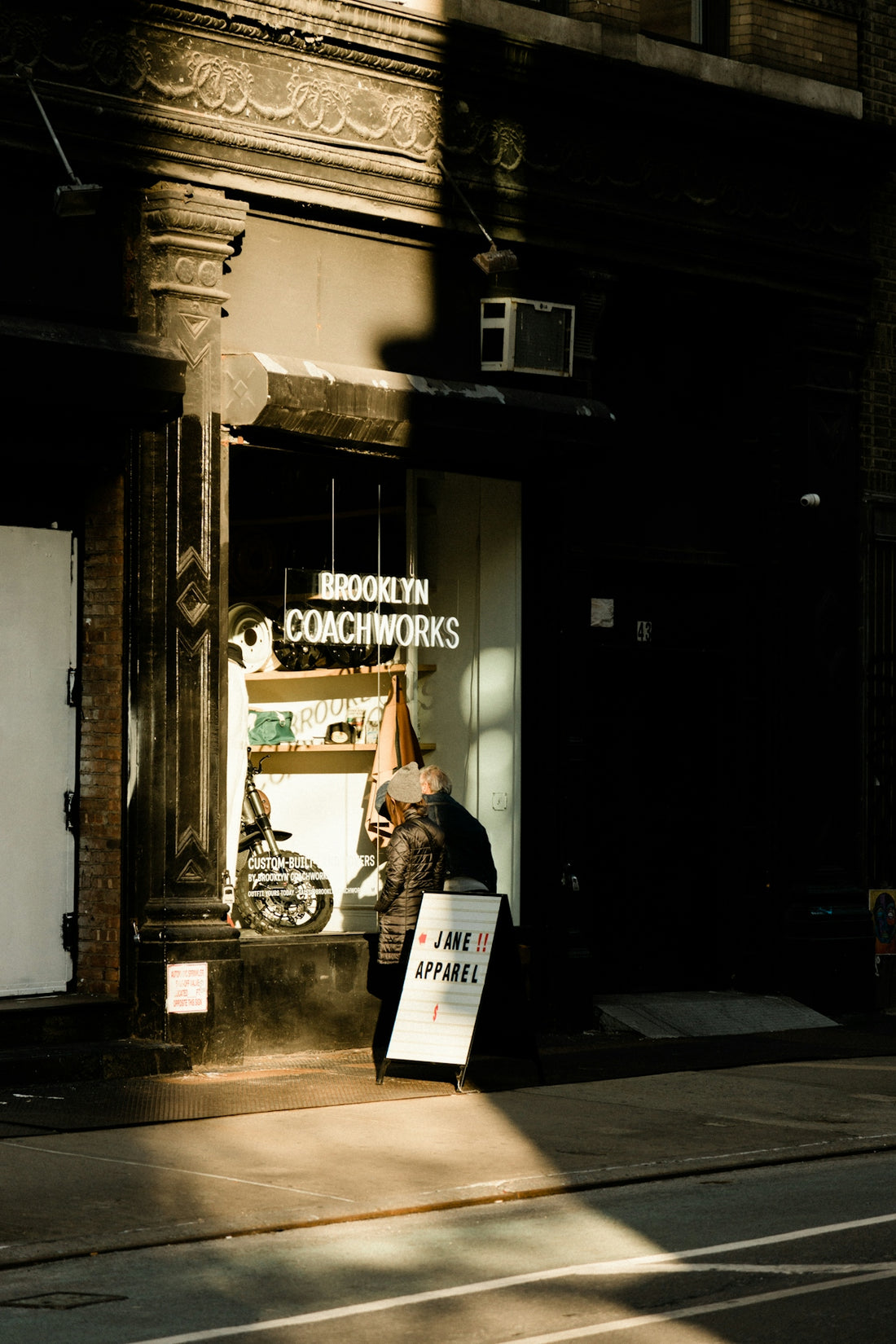 a woman walking down a street past a store
