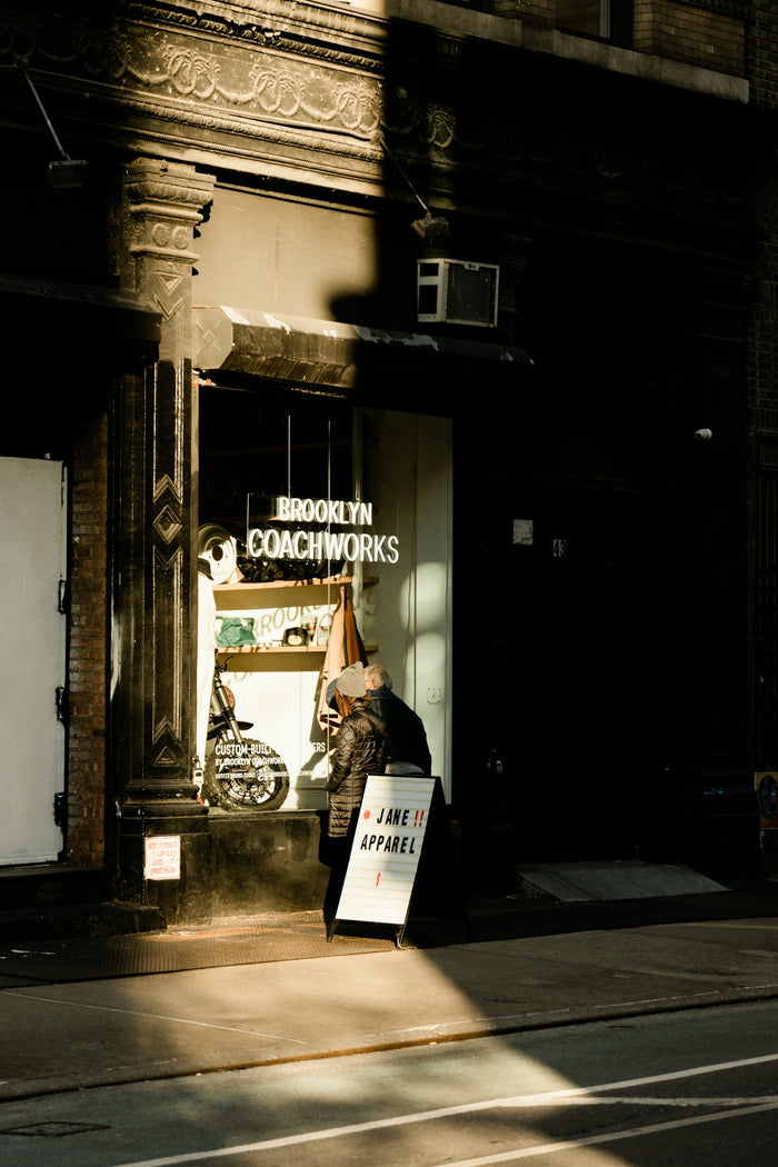 a woman walking down a street past a store