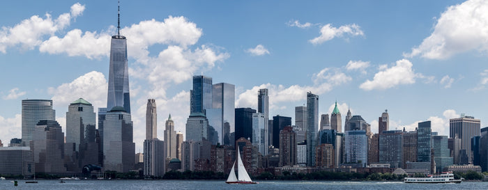 a sailboat on the water in front of a large city