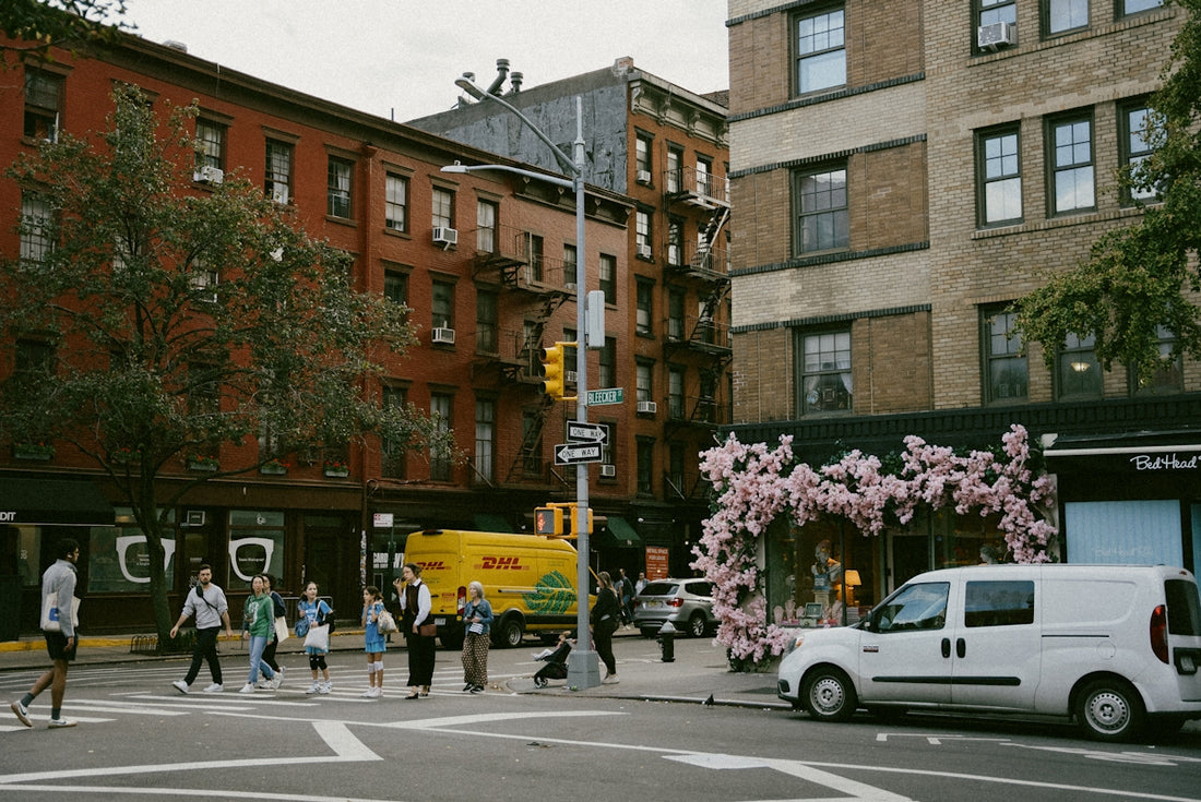 A group of people walking across a street next to tall buildings