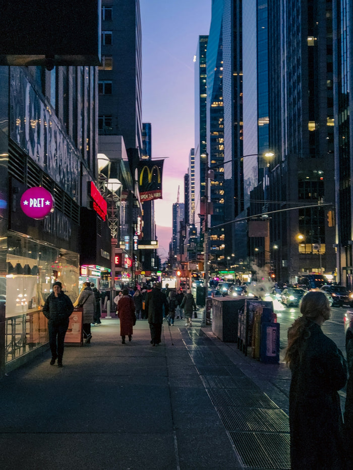 A group of people walking down a street next to tall buildings