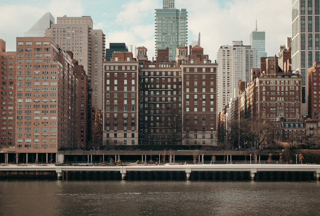 Buildings line a river in a cityscape.