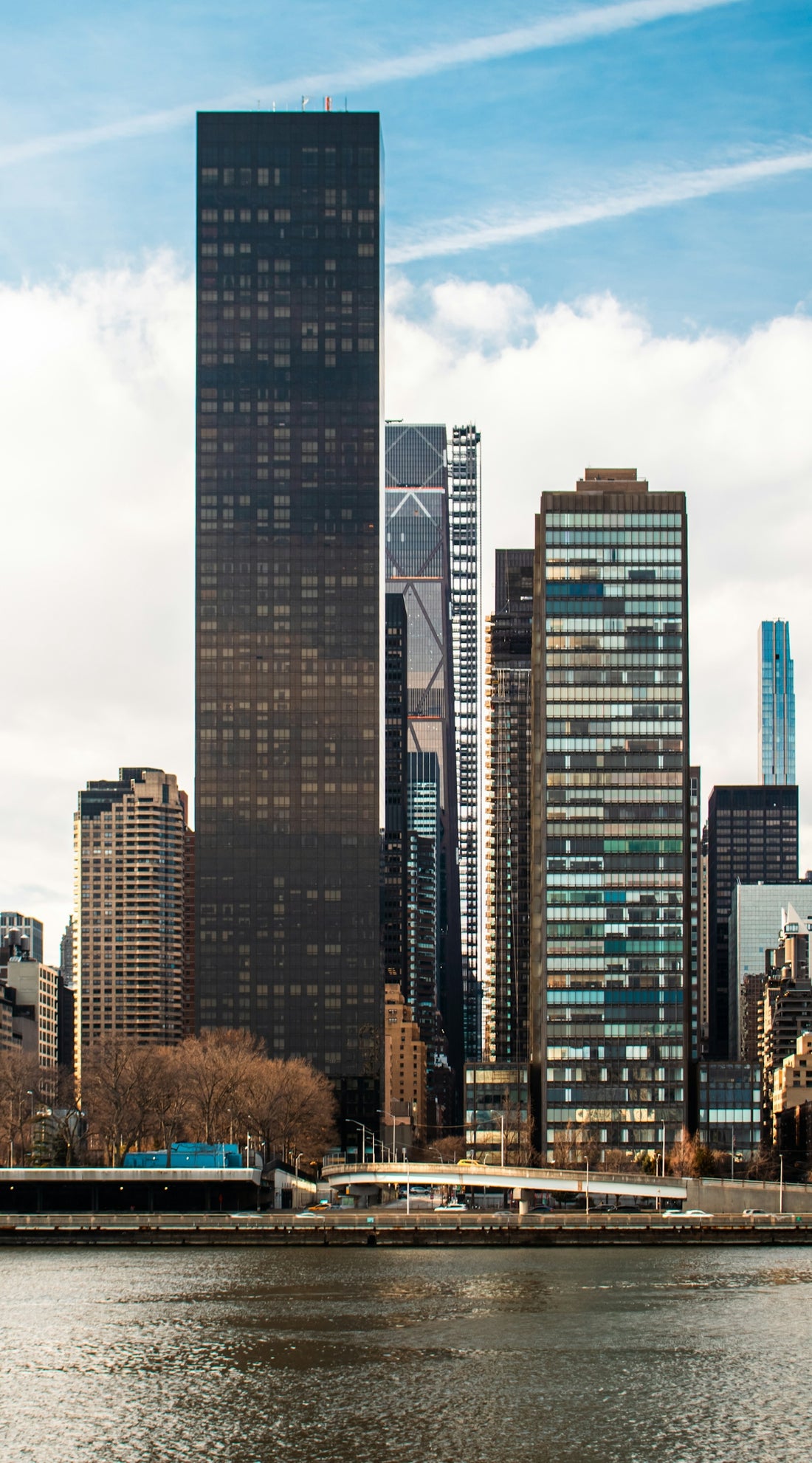 Skyscrapers stand tall against a blue, cloudy sky.