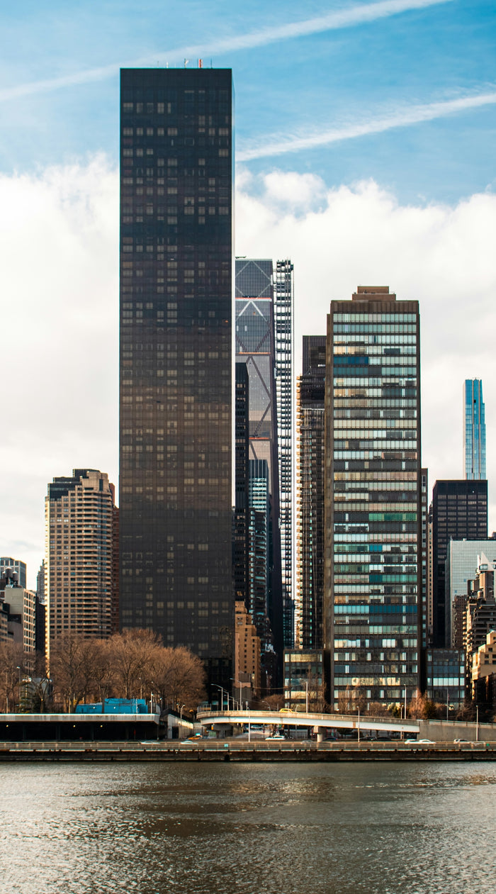Skyscrapers stand tall against a blue, cloudy sky.