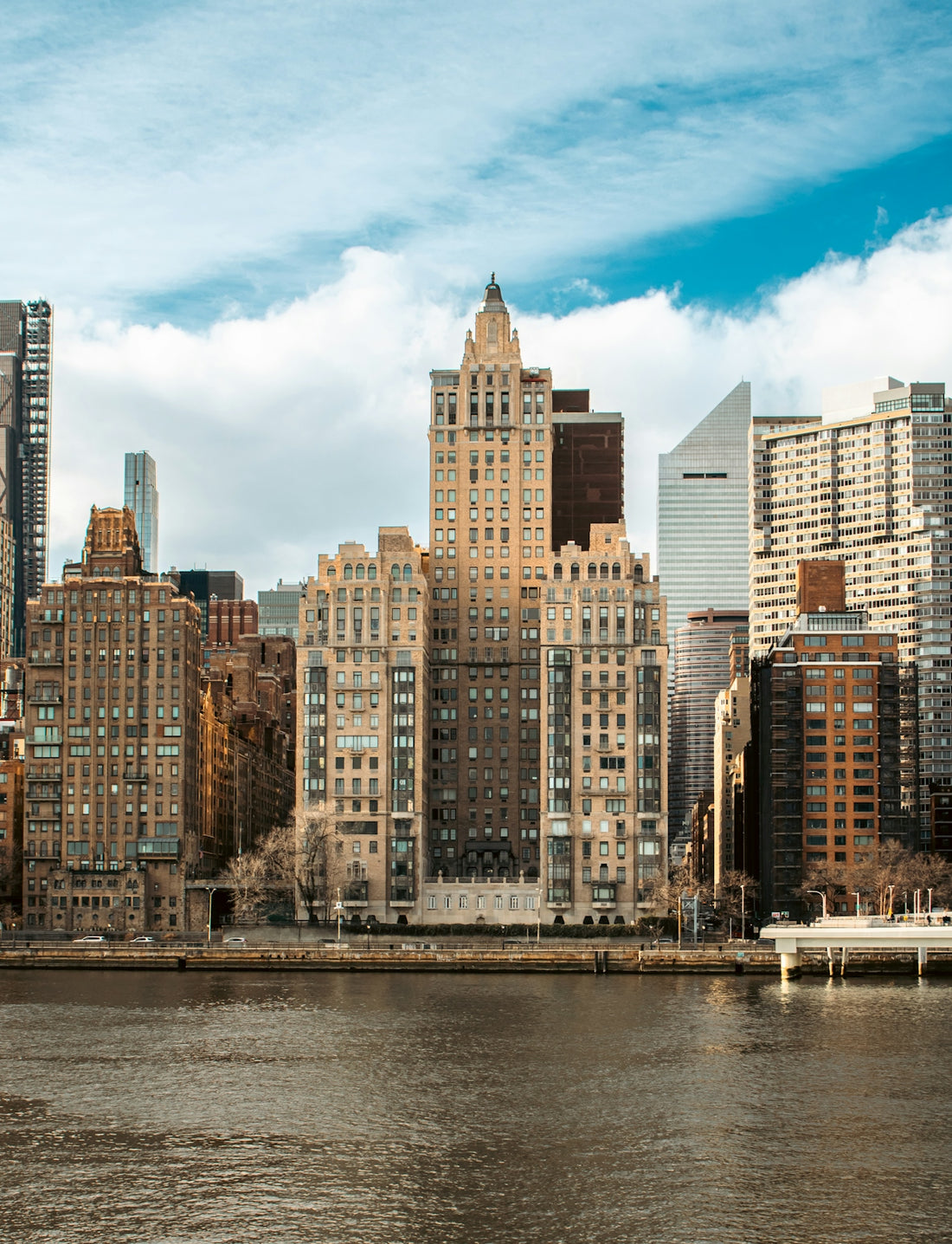 Skyscrapers line a body of water in new york.