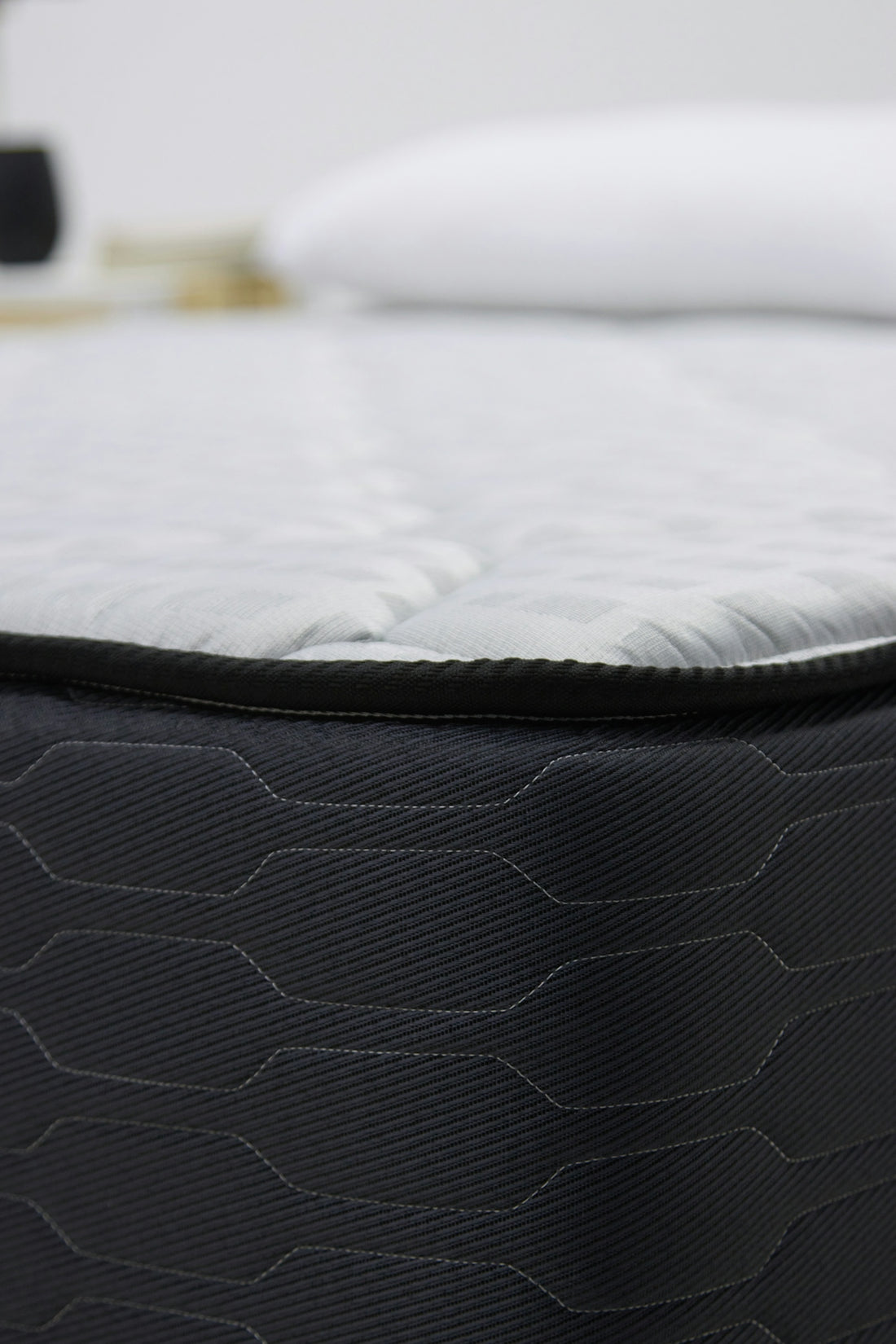 Close-up of a dark gray mattress with white bedding