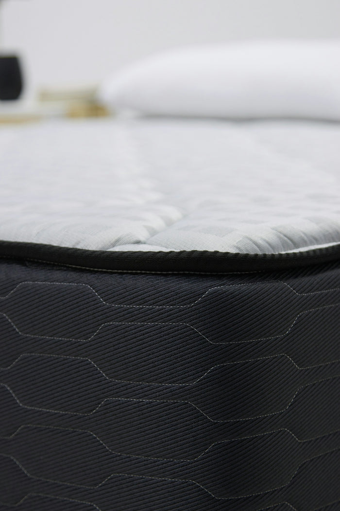 Close-up of a dark gray mattress with white bedding