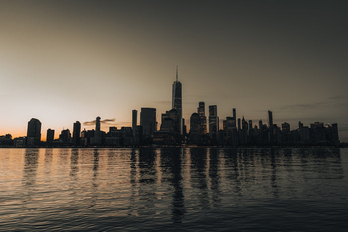 City skyline reflected in calm water at sunset