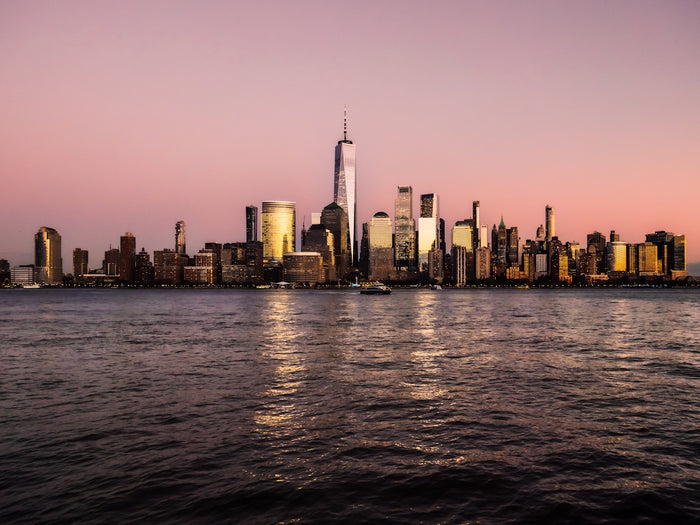 Manhattan skyline at sunset with water reflection