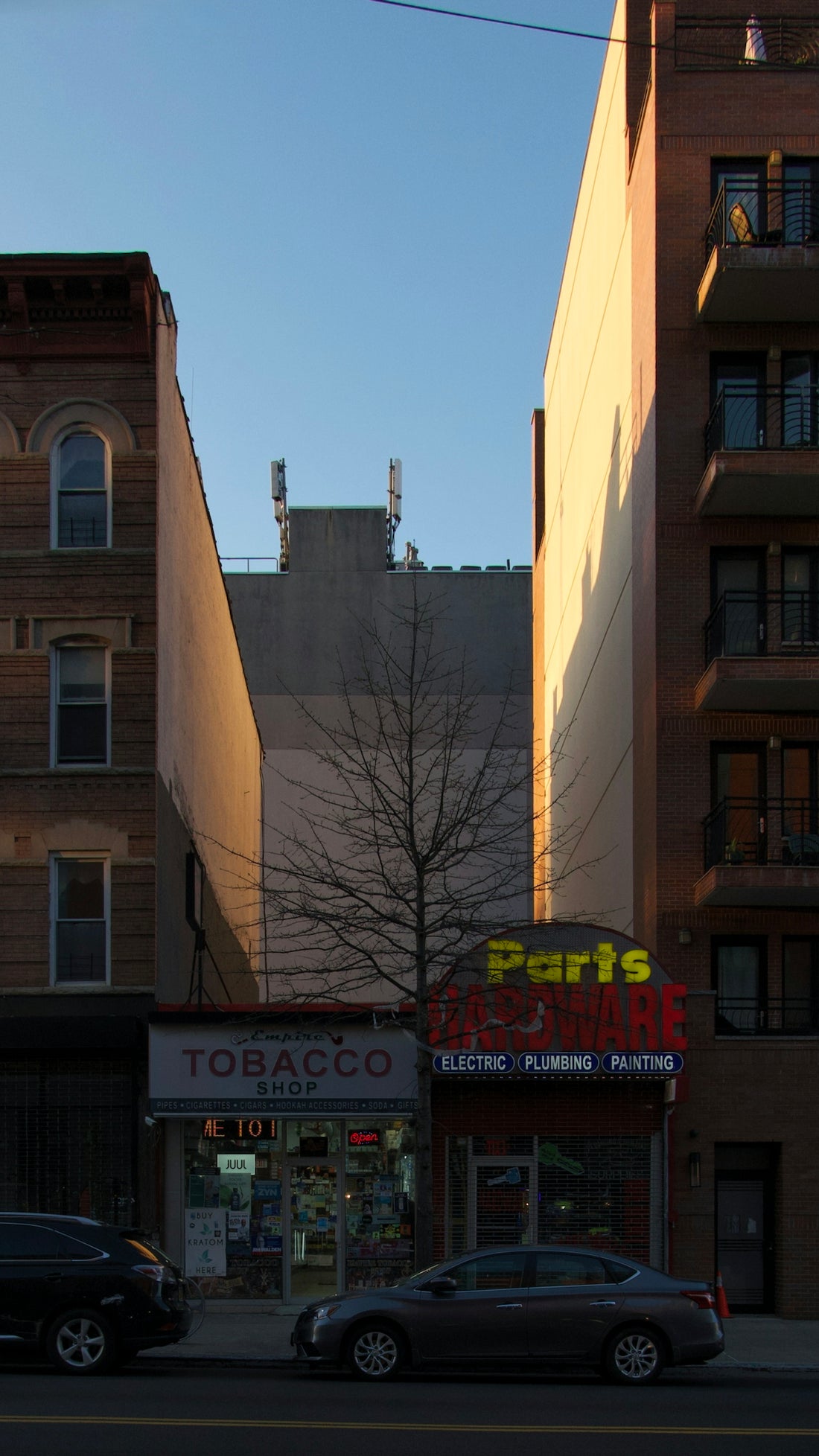 Buildings and cars on a street with shops.
