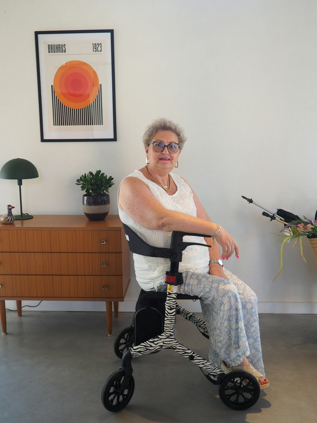 Smiling older woman sitting on a stylish zebra-print walker indoors