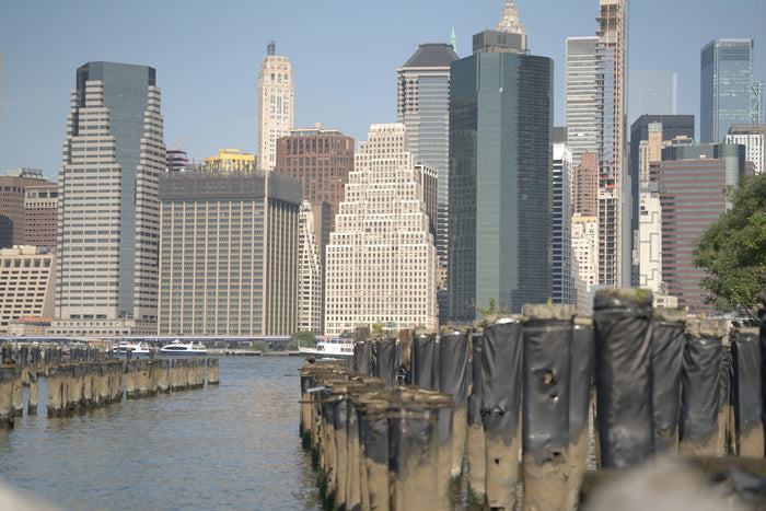 The Manhattan skyline viewed across the water from a row of wooden pilings.